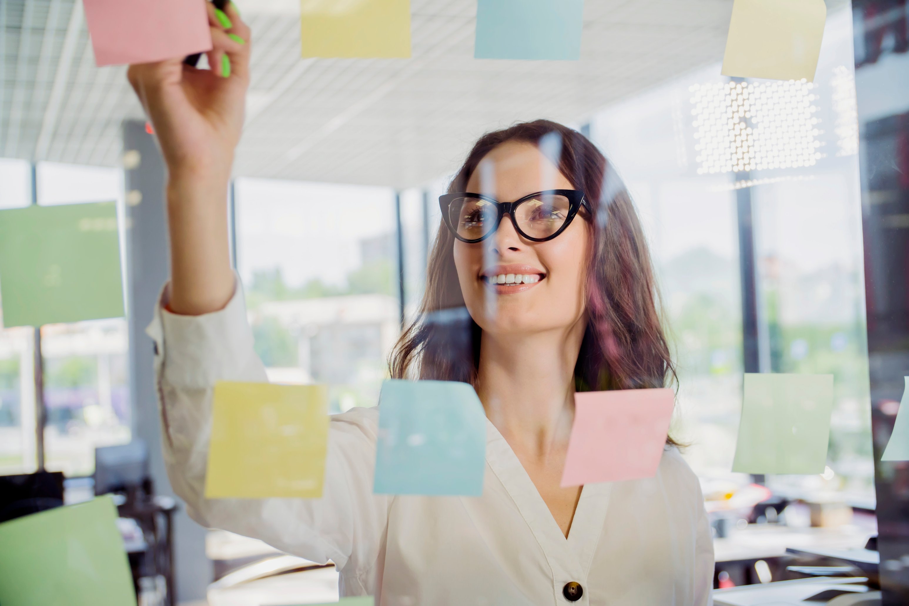 Frau beim post-it kleben Glaswand_de Art_AdobeStock_287653133