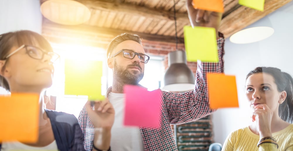 Mitarbeiter vor Post-it Wand